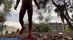 En muskulös man visar upp sin kondition genom att göra nakna knäböj utomhus